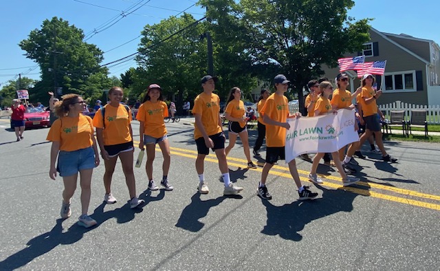 A group of teens wearing orange march in a parade