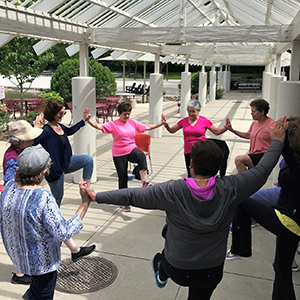 A multi-ethnic, multi-age group of people hold hands doing exercises