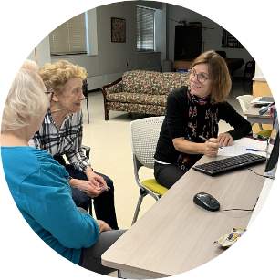 A middle aged woman discusses healthcare options with two seniors